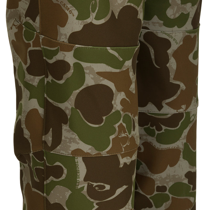 A pair of Pursuit Tech Stretch Pants with Agion Active XL® in camouflage pattern, designed for durability and comfort during cool to cold days afield. Made of 100% polyester bonded fleece fabric with 4-way stretch. Features zippered hip vents, strategically placed zippered pockets, and a lightweight design. Ideal for early-mid season big game hunting.