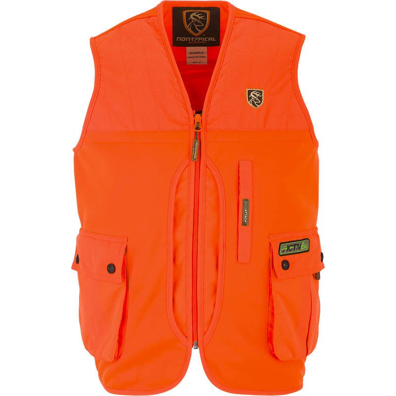Youth Blaze Orange Vest with Agion Active XL, featuring vertical chest pockets, a front load game bag, and a large rear zippered pass-through storage pocket. Side entry fleece-lined hand warmer pockets and a logo on an orange surface.