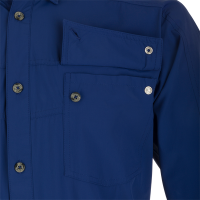 A close-up of the Performance Mesh Paneled Short Sleeve Shirt, featuring a blue fabric with button-through flap chest pockets and a hidden button-down collar. The shirt has laser-punched mesh back panels for increased ventilation and offers UPF 50 sun protection, moisture-wicking, and quick-drying properties. Perfect for outdoor activities.