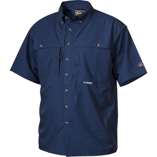 A blue short sleeved shirt with buttons, made from StayCool™ cotton blended fabric. Perfect for outdoor activities or casual office wear. Features front and back ventilation, oversized chest pockets, and a vertical zippered pocket. Stay cool and comfortable in this Cotton Wingshooter's Shirt with StayCool™ Fabric S/S.