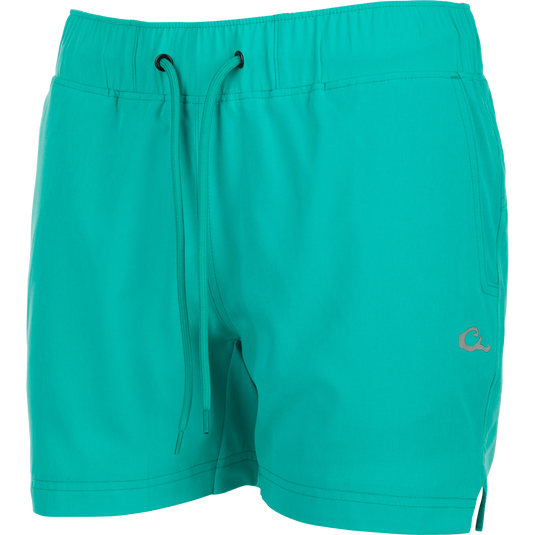 Women's Commando Lined Short 7" with turquoise shorts, zipper close-up, and blue fabric. Versatile gym or beach short with 4-way stretch, quick-drying fabric, and moisture-wicking liner. Scalloped hem, elastic waistband with drawstring, and multiple pockets.