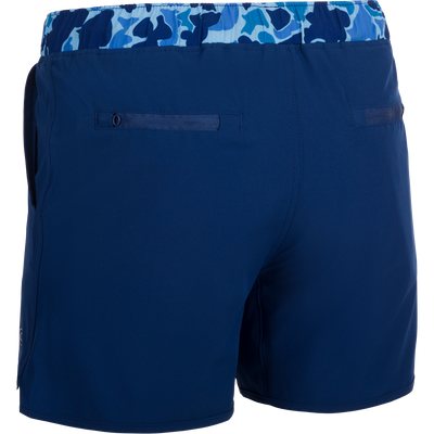 A versatile pair of blue shorts with a built-in liner, perfect for the playground or beach. Made with quick-drying, moisture-wicking fabric and a 4-way stretch for comfort. Features include scalloped hem, adjustable drawstring waistband, and multiple pockets. Youth Commando Lined Volley Short 5 from Drake Waterfowl.