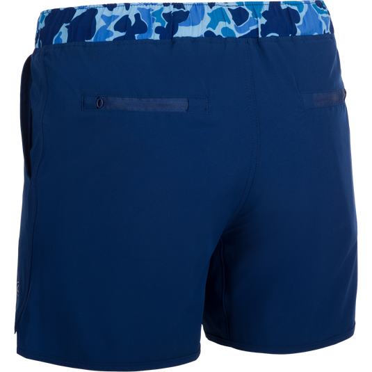 A versatile pair of blue shorts with a built-in liner, perfect for the playground or beach. Made with quick-drying, moisture-wicking fabric and a 4-way stretch for comfort. Features include scalloped hem, adjustable drawstring waistband, and multiple pockets. Youth Commando Lined Volley Short 5 from Drake Waterfowl.