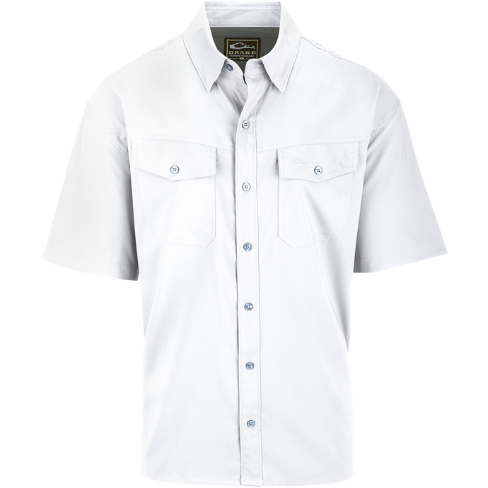 A white shirt with buttons, hidden button-down collar, and two chest pockets. Made of 100% Polyester textured dobby fabric, it's lightweight, moisture-wicking, and offers UPF30 sun protection. The Traveler's Solid Dobby Shirt S/S is versatile for any occasion.