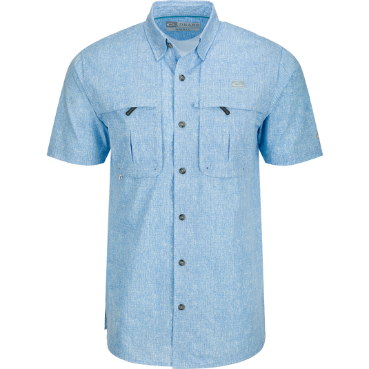 A Drake Heritage Heather Shirt S/S, a blue button-up shirt with pockets, made of 100% polyester micro mesh for natural cooling and quick drying. Features include a hidden button-down collar, vented cape back, and split tail hem. Perfect for performance on the water or at the office.