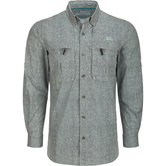 Heritage Heather Shirt L/S: A grey long-sleeved shirt with hidden button-down collar, vented cape back, and two front chest pockets. Lightweight, moisture-wicking fabric with UPF30 sun protection. Perfect for performance and comfort on the water or at the office.