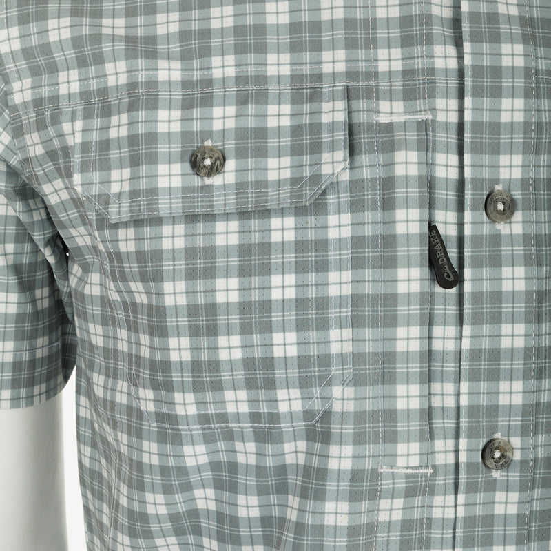 A close-up of the Drake Hunter Creek Check Plaid Shirt, featuring a hidden button-down collar, vented back cape, and two button-through flap chest pockets with a hidden zipper pocket. Sculpted hem allows for tucked or untucked wear. Lightweight micro-mesh fabric with UPF30 sun protection and moisture-wicking properties. Perfect for outdoor activities.