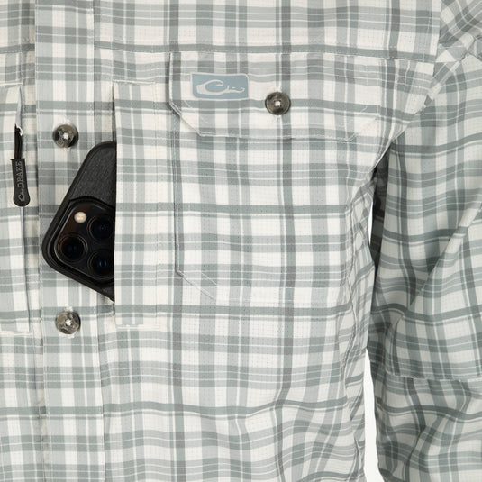 Hunter Creek Window Pane Plaid Shirt L/S: A cell phone in a shirt pocket, showcasing the shirt's hidden button-down collar, vented back cape, and two chest pockets with zipper and Magnattach closures.