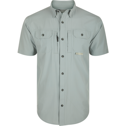Wingshooter Trey Shirt S/S: Close-up of performance shirt with hidden collar, chest pockets, and vented back, featuring technical fabric and functional design: Quarry