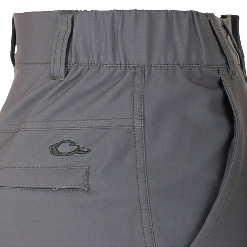 A close-up of the Traveler Trek Pant, a grey pants with a spiral detail. Made from 90% Polyester and 10% Spandex, it's lightweight, stretchy, and quick-drying. Features include articulated knees, multiple pockets, and a comfortable elastic waistband. Perfect for your next adventure.