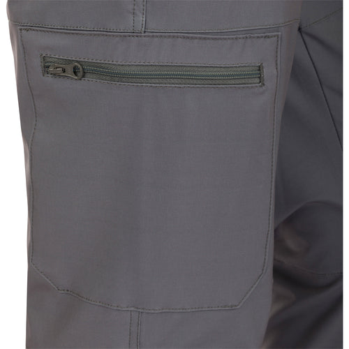 A close-up of the Traveler Trek Pant pocket with a zipper on khaki fabric.
