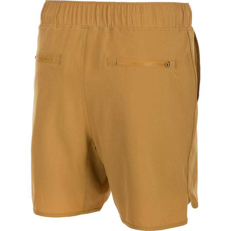 A pair of tan Commando Lined Volley Shorts with a 7-inch inseam. Features include 4-way stretch, moisture-wicking, and quick-drying fabric. The shorts have a fully elasticized waistband with an adjustable drawstring, front slash pockets, and back zippered pockets. The built-in liner is quick-drying and has the Drake Old School Camo print. Perfect for beach to bar versatility.