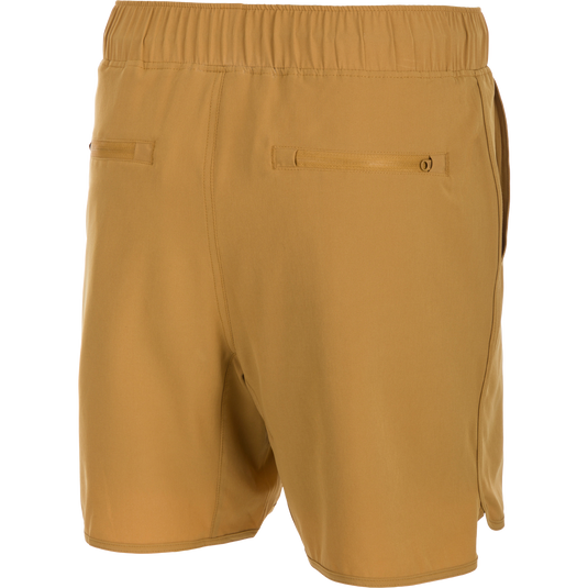 A pair of tan Commando Lined Volley Shorts with a 7-inch inseam. Features include 4-way stretch, moisture-wicking, and quick-drying fabric. The shorts have a fully elasticized waistband with an adjustable drawstring, front slash pockets, and back zippered pockets. The built-in liner is quick-drying and has the Drake Old School Camo print. Perfect for beach to bar versatility.