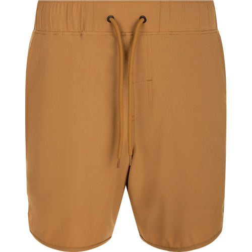 A pair of tan Commando Lined Volley Shorts with a string, scalloped hem, and hidden zipper pockets. 7-inch inseam, built-in liner, and elastic waistband with drawstring. Versatile and quick-drying for beach to bar wear.
