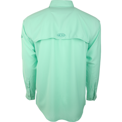 A close-up of the Flyweight Shirt with Vented Back L/S, a green shirt with a logo. Designed for warm-weather outdoor activities, it's made of ultra-lightweight polyester with UPF 50+ sun protection. Quick-drying, moisture-wicking, and breathable, it features a vented mesh back and horizontal chest pockets. Perfect for hunting, fishing, and other outdoor adventures.