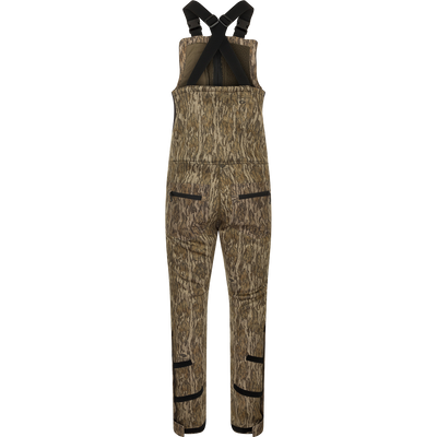 A brown overalls with black straps, featuring a four-way stretch material, gusseted crotch, and articulated knees for ease of movement. Includes Sherpa-lined slash handwarmer pockets, Magnattach™ left chest pocket, and zippered rear security pockets. MST Ultimate Wader Bib.