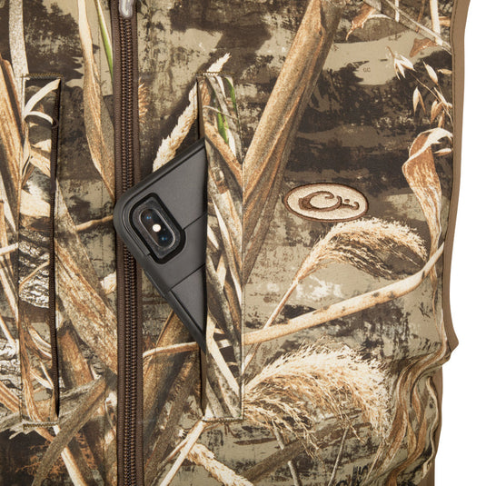 A close-up of the EST Camo Windproof Tech Vest with a phone in the chest pocket and a logo on the side.