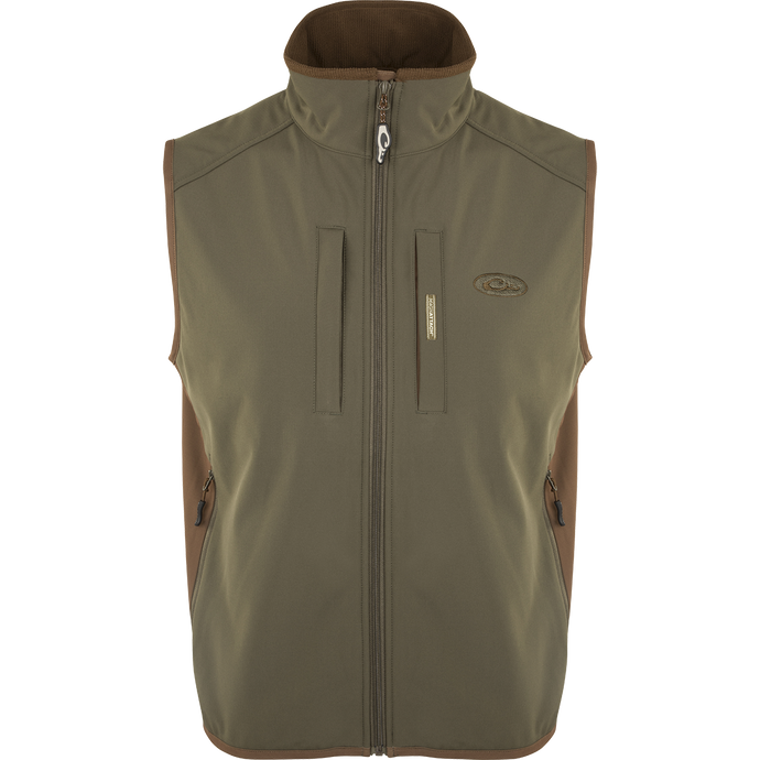 EST Windproof Tech Vest, featuring a logo and zipper details. This khaki vest is made of high-quality polyester tech shell and bonded fleece lining with a windproof membrane. It's perfect for outdoor activities and can be worn as a core or outer layer. Stay warm and stylish with this versatile vest from Drake Waterfowl.