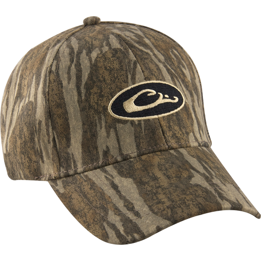 Camo Cotton Cap with logo, perfect for outdoor enthusiasts. Lightweight and comfortable, it features camo concealment under the bill to reduce glare. Six-panel construction and hook and loop closure for a secure fit. Made with 100% cotton. From Drake Waterfowl, your go-to store for high-quality hunting gear and clothing.