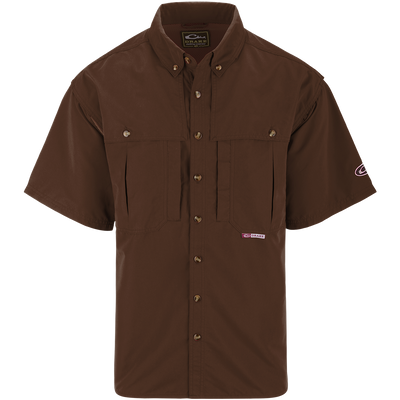 A brown short sleeved shirt with a logo on the chest, perfect for outdoor activities. Features include front and back ventilation, oversized chest pockets, and a zippered pocket. Made with wrinkle-resistant EasyCare™ fabric and a poly-mesh lining for breathability. From Drake Waterfowl, known for high-quality hunting gear and clothing.