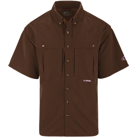 A brown short sleeved shirt with a logo on the chest, perfect for outdoor activities. Features include front and back ventilation, oversized chest pockets, and a zippered pocket. Made with wrinkle-resistant EasyCare™ fabric and a poly-mesh lining for breathability. From Drake Waterfowl, known for high-quality hunting gear and clothing.