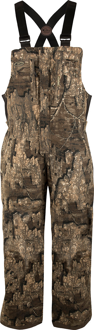A pair of camouflage shorts with full-length zippers on each side for easy removal. Made with waterproof, windproof, and breathable materials, reinforced knees and seat, and fleece-lined hand warmer pockets. LST Youth Refuge Insulated Bibs from Drake Waterfowl.