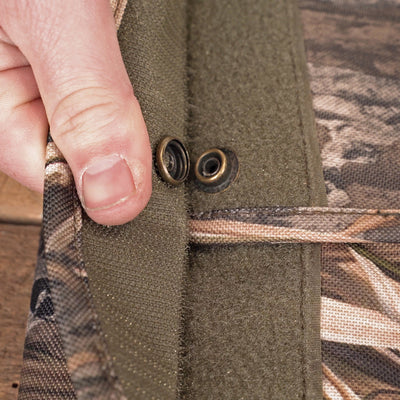 A person's hand holding a button on a side-opening gun case with a fabric pocket and metal object.