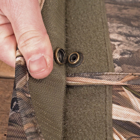 A person's hand holding a button on a side-opening gun case with a fabric pocket and metal object.