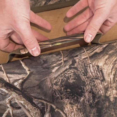 A person holding a camouflage bag for the Side-Opening Gun Case by Drake Waterfowl.