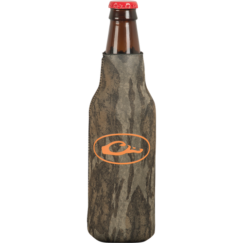 A brown glass bottle with a red cap, featuring an orange logo on a grey surface. The bottle cooler has a side zipper for a snug fit and a separate bottom piece to prevent tipping over.