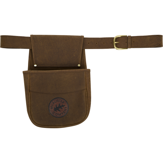 A brown leather belt pouch with a logo, perfect for carrying ammunition or empty shell cases. Made with top-grain water buffalo leather, brass hardware, and an adjustable leather belt. Durable and stylish.