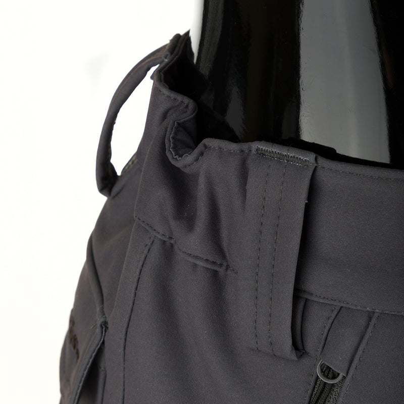 McAlister Microfleece Softshell Waterfowler's Pants: Close-up of black pants with bag, zipper, and fabric details. Features side-elastic waist, silicone grip waistband, 4-way stretch, gusseted crotch, articulated knees, and multiple zippered pockets. Versatile and comfortable hunting gear.