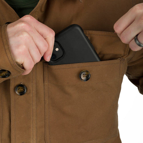 A person putting a phone in the pocket of the McAlister Waxed Cotton Jac-Shirt, showcasing its functional fit and heritage look.