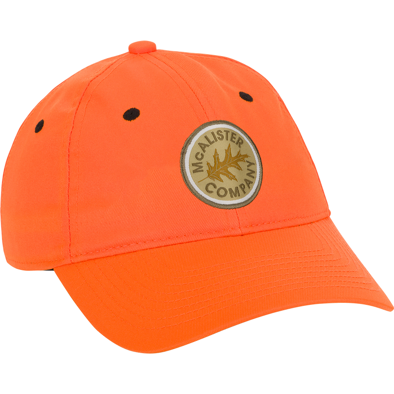 McAlister Upland Circular Patch Twill Cap: A low-profile, orange baseball cap with a logo patch. Adjustable Velcro closure for a perfect fit.