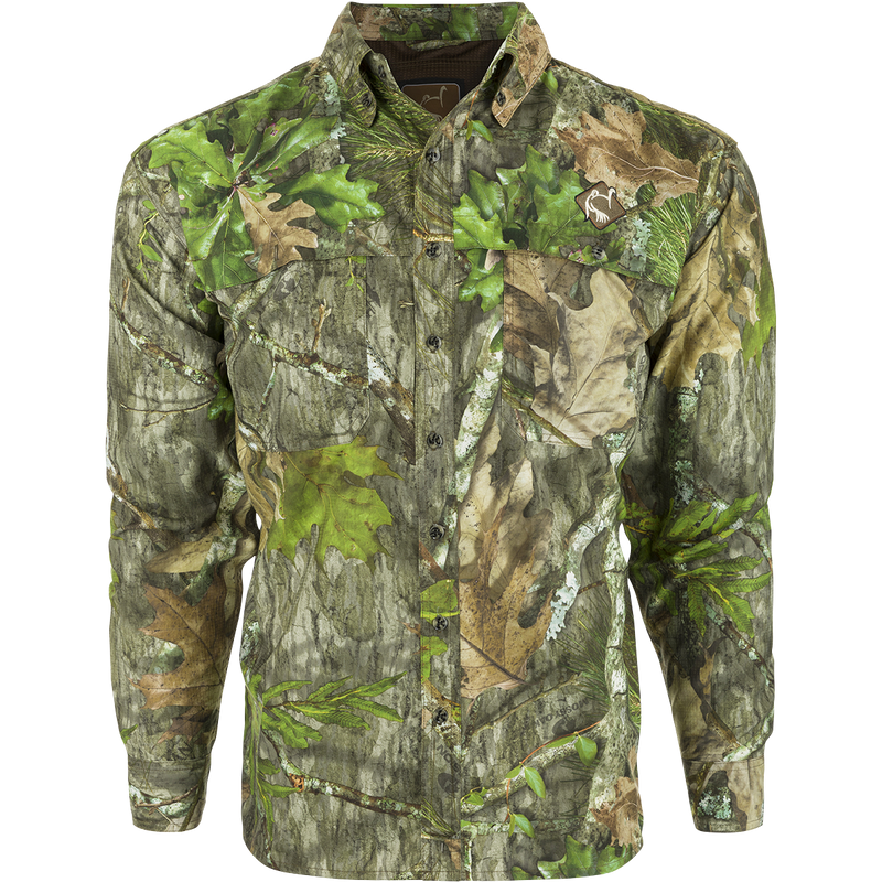 A close-up of a camouflage-patterned long-sleeved shirt with a mesh back panel and large chest pockets. The shirt is made of lightweight, breathable polyester and features a removable spine pad for increased comfort while hunting.