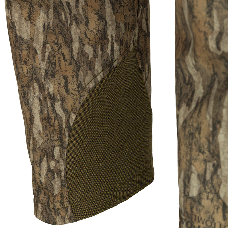 A close-up of the Men's Tech Stretch Turkey Hunting Pant, featuring a camouflage pattern. Designed for spring turkey season, these lightweight, moisture-wicking pants offer 4-way stretch and reinforced knees and ankles. Stay comfortable and concealed in the woods with this durable hunting gear from Drake Waterfowl.