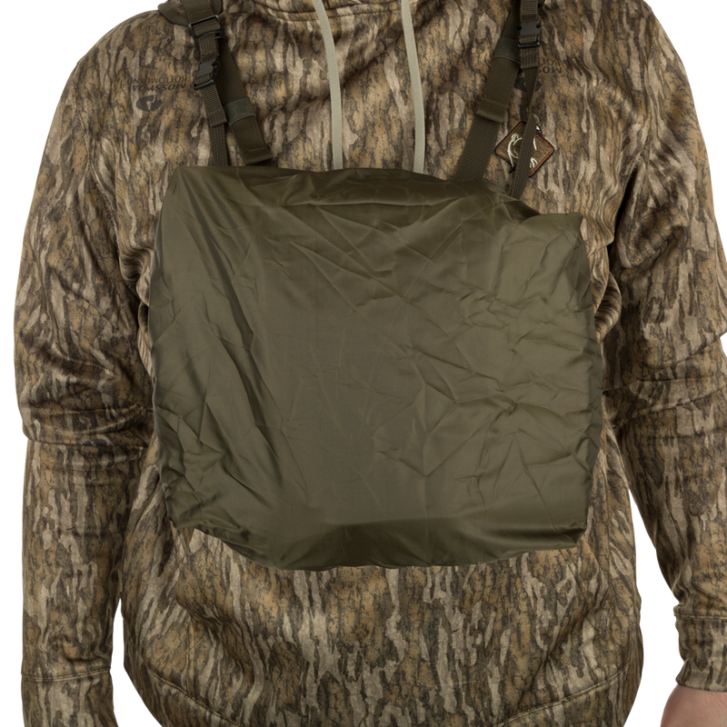 A person wearing the Turkey Chest Pack, a camouflage jacket with multiple pockets and loops for hunting.