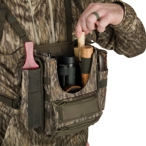 A person in camouflage holding the Turkey Chest Pack, a lightweight hunting companion with multiple pockets and loops for a successful hunt.