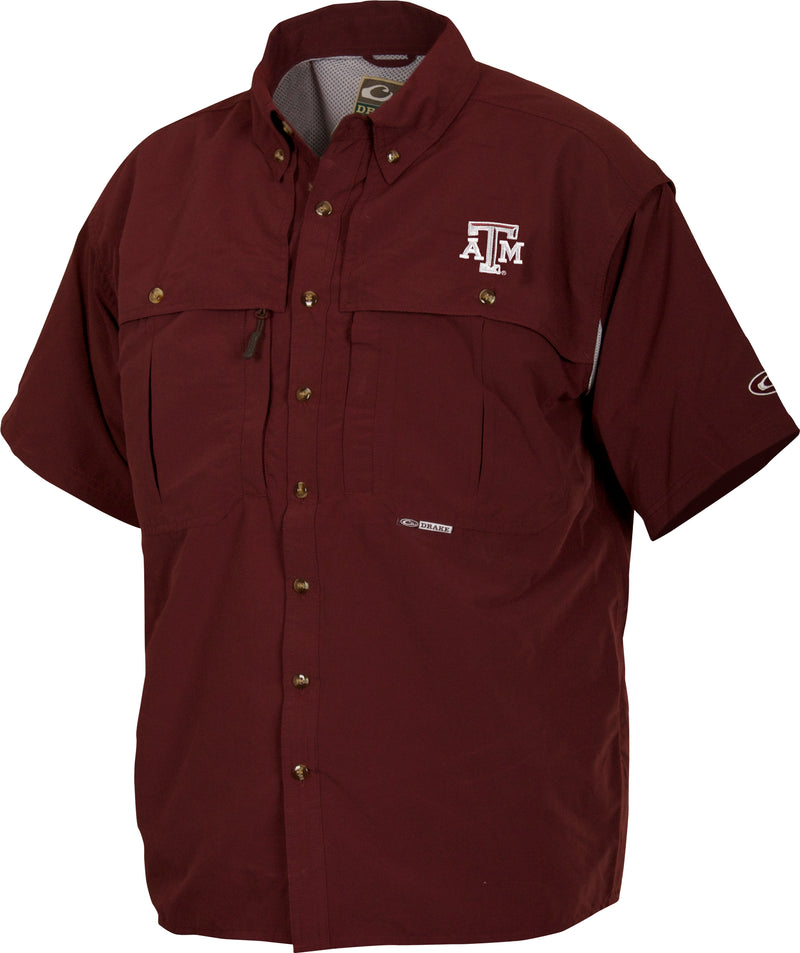 A maroon short-sleeved shirt with a logo close-up. Breathable and quick-drying, perfect for Game Day. Features include front and back ventilation, oversized chest pockets, and a zippered pocket. Texas A&M Wingshooter's Shirt S/S.
