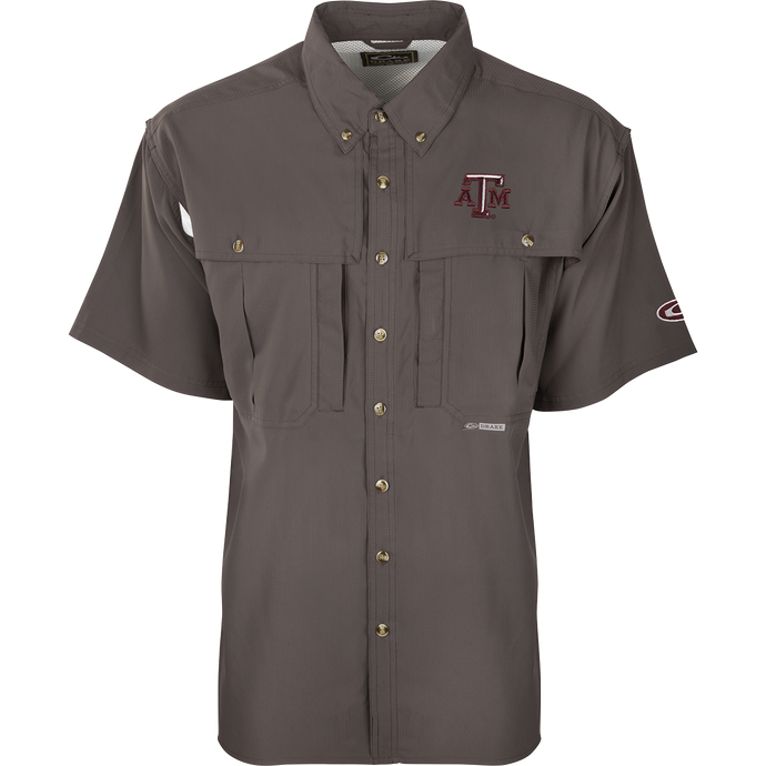 Texas A&M S/S Flyweight Wingshooter: A grey shirt with a logo, designed for warm-weather outdoor activities. Made of ultra-lightweight polyester fabric that dries quickly and wicks moisture away. Features include UPF 50+ sun protection, vented back, chest pocket, and zipper pocket.