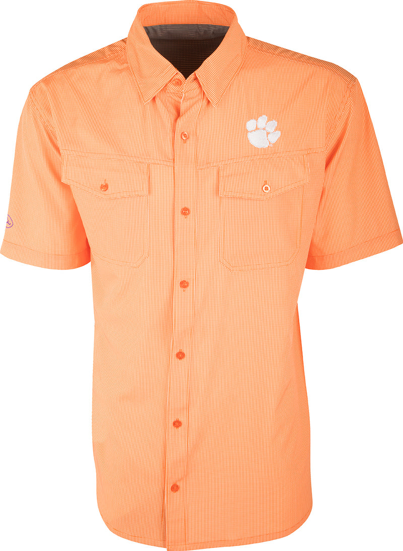 Clemson S/S Traveler's Shirt: A lightweight, wrinkle-resistant shirt with a paw print on a checkered surface. Ideal for early season football games or weekend tailgates with friends. Moisture-wicking fabric with four-way stretch for freedom of movement. 2 chest pockets with button flaps. Clemson logo embroidered on the left chest.