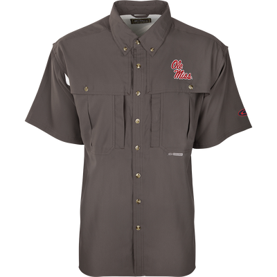 A close-up of the Ole Miss S/S Flyweight Wingshooter shirt, featuring a logo on a grey background. Made with ultra-lightweight polyester, it offers quick-drying, moisture-wicking, and breathable properties. Includes Sol-Shield™ UPF 50+ sun protection, Magnattach™ vertical chest pocket, and a vertical zipper pocket. Ideal for warm-weather outdoor activities.