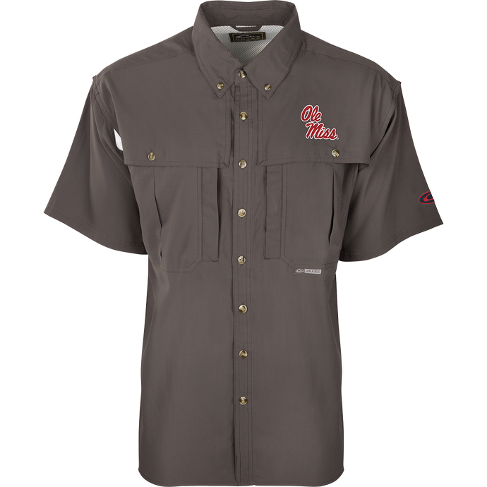 A close-up of the Ole Miss S/S Flyweight Wingshooter shirt, featuring a logo on a grey background. Made with ultra-lightweight polyester, it offers quick-drying, moisture-wicking, and breathable properties. Includes Sol-Shield™ UPF 50+ sun protection, Magnattach™ vertical chest pocket, and a vertical zipper pocket. Ideal for warm-weather outdoor activities.