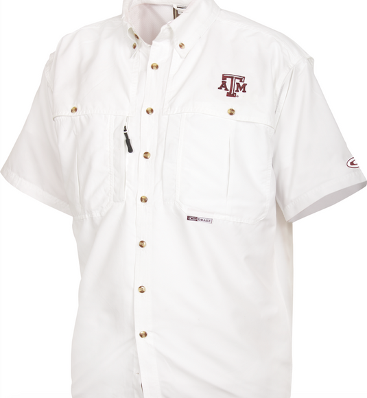 A white Texas A&M Wingshooter's Shirt with a logo on it. Breathable, cool, and quick-drying. Features front and back ventilation, oversized chest pockets, and a zippered pocket. Perfect for Game Day.