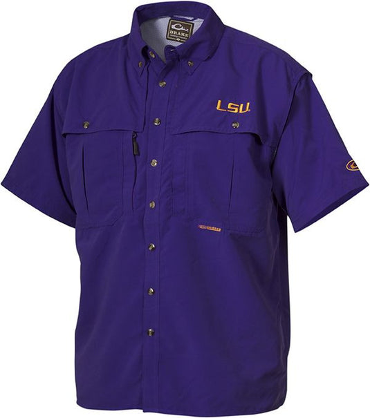 LSU Wingshooter's Shirt S/S: Breathable purple shirt with logo. Seven-button design with front and back ventilation for coolness and moisture management. Features oversized chest pockets, Magnattach™ pocket, and zippered pocket. Perfect for Game Day. Made with 100% polyester twill fabric and poly-mesh lining in vented areas. Wrinkle-resistant EasyCare™ fabric. From Drake Waterfowl, a store known for high-quality hunting gear and clothing.