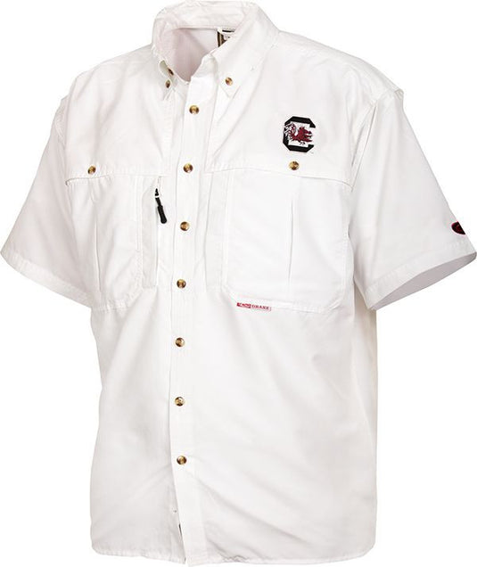 South Carolina Wingshooter's Shirt S/S: A white shirt with buttons, a logo, and vented areas for breathability and moisture management. Features include chest pockets, a zippered pocket, and a Magnattach pocket. Made of polyester twill fabric with a poly-mesh lining. Ideal for Game Day.
